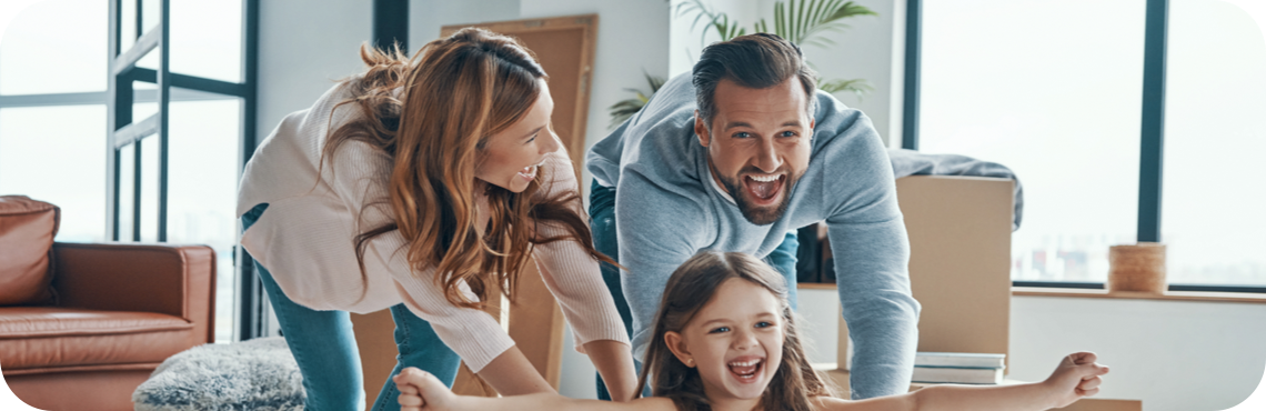A family standiing in front of a grey house on a sunny day